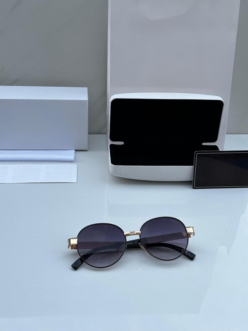 Top view of SRK Style Gold Round Sunglasses, showing full packaging contents (case, cloth, card).
