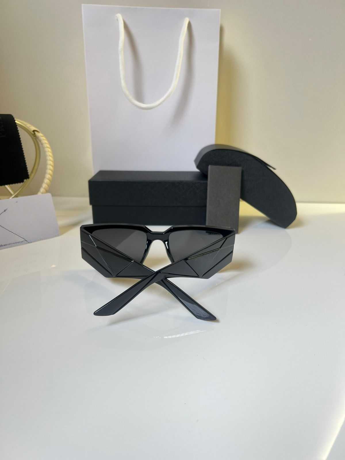Ultra-bold black angular rectangle sunglasses with unique winged temple design, displayed with packaging.