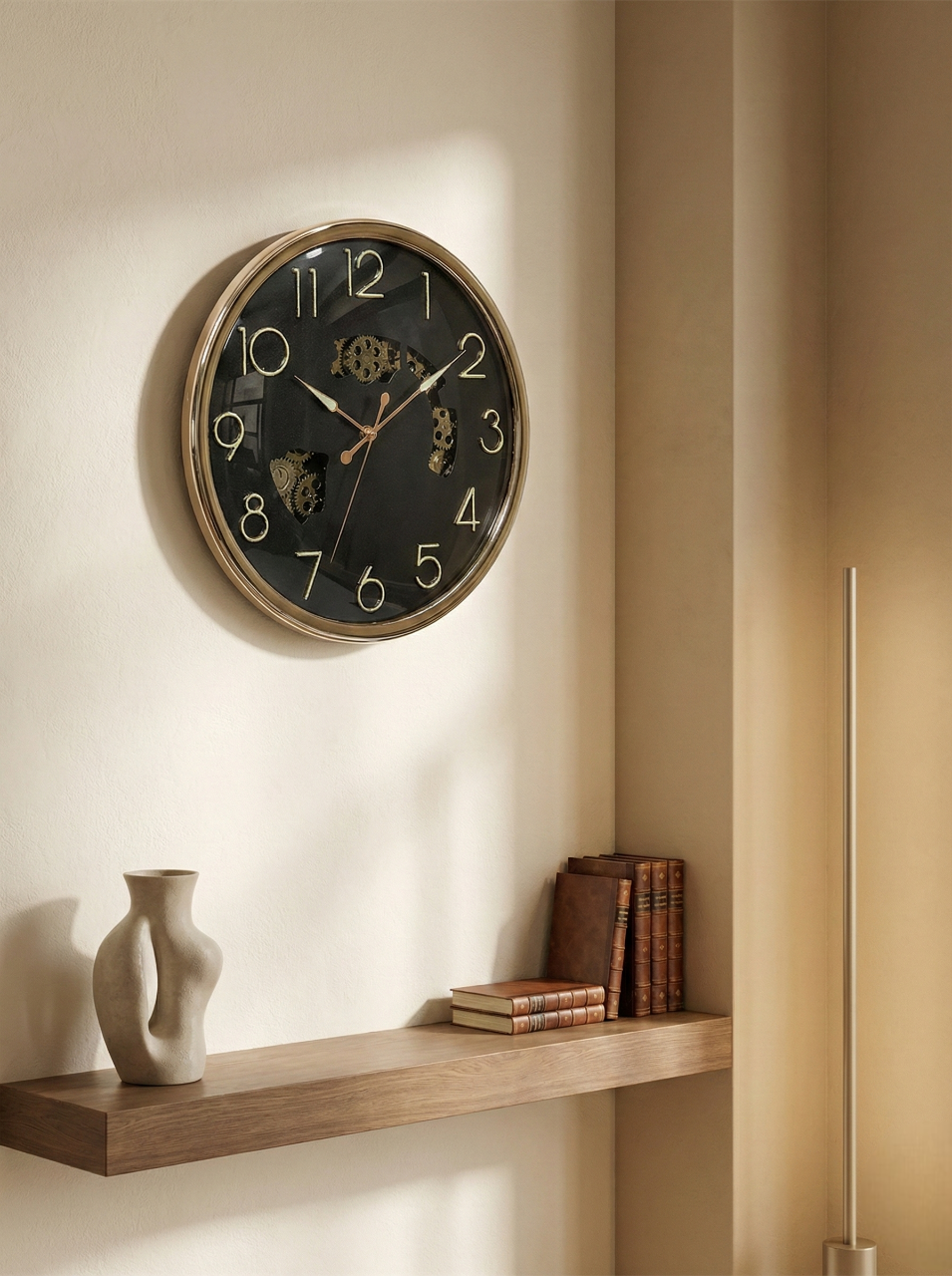 Wall clock on a beige wall with a shelf below containing books and a vase.