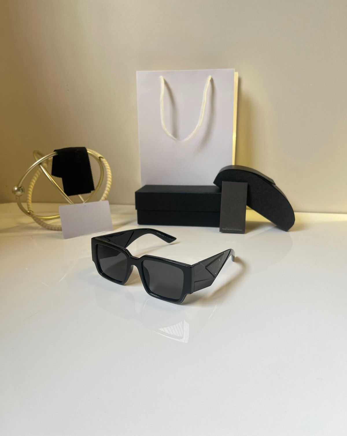 Ultra-bold black angular rectangle sunglasses with unique winged temple design, displayed with packaging.